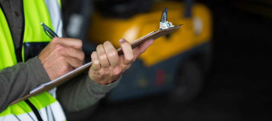Male worker writing on clipboard in warehouse